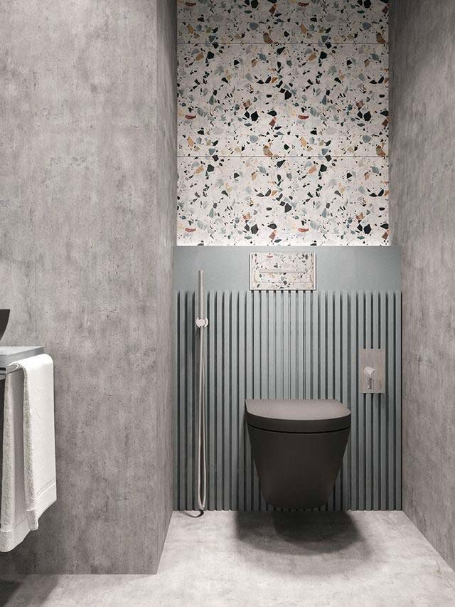 Des toilettes contemporaines avec du mur en béton ciré et un pan de mur en terrazzo graphique