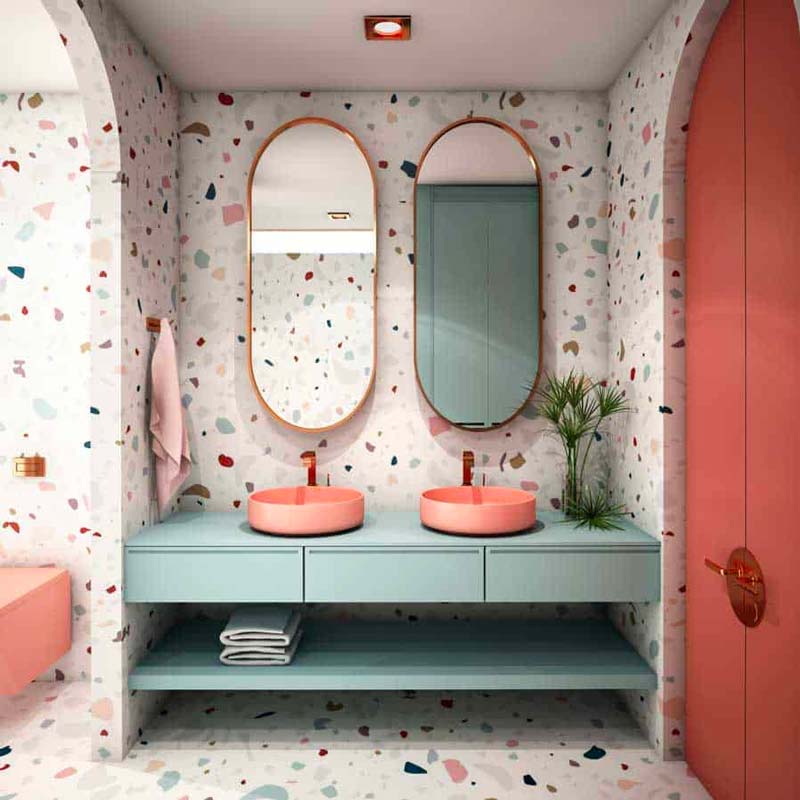 Une salle de bain vintage mouchetée de terrazzo en total look, mobilier vert sauge, vasques terracotta et miroirs ovales