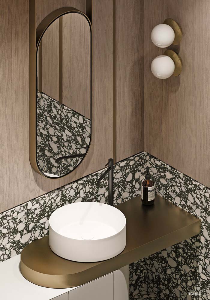 Salle de bain en terrazzo et bois clair avec vasque ronde, miroir oval et luminaire circulaire