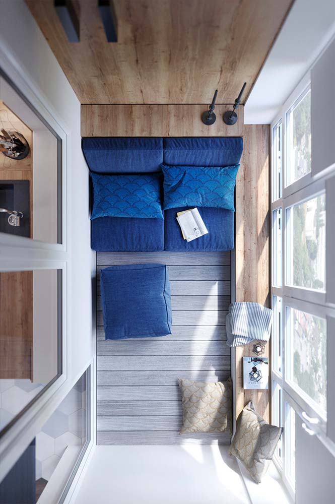 Balcon fermé agencé sur-mesure avec du bois clair et une banquette bleu roi