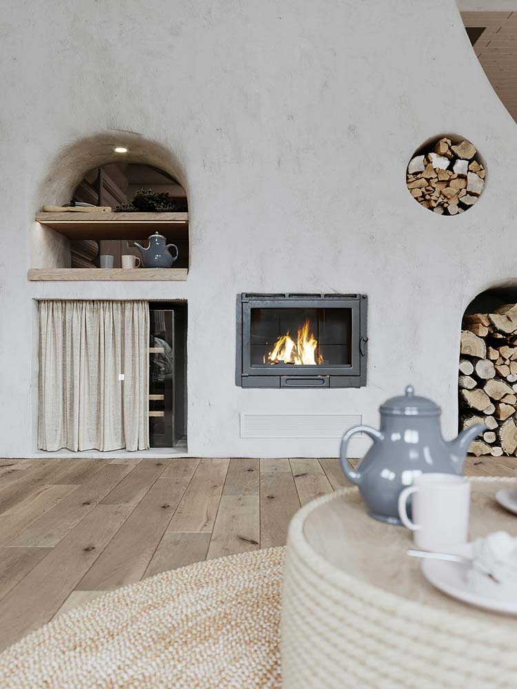 Un salon campagne chic avec un mur blanc simple, plancher en bois et table basse en corde avec quelques accessoires déco en bois et porcelaine