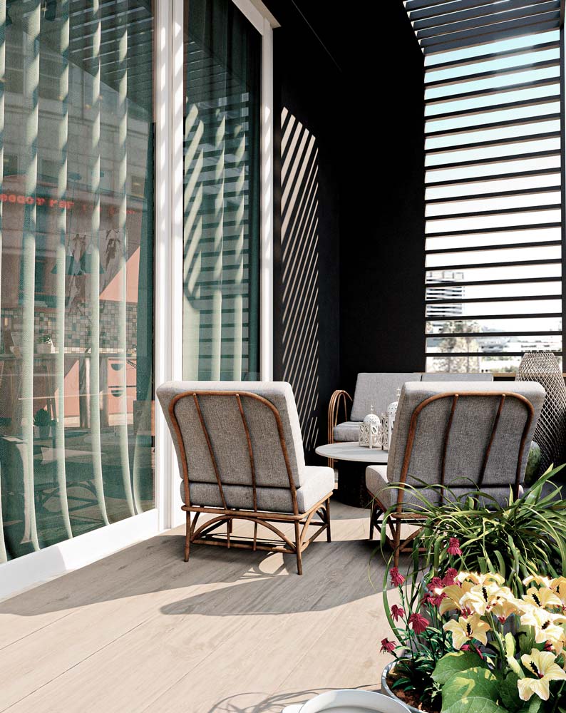 Un petit salon extérieur sur un balcon au parquet clair avec des assises confortables gris et osier