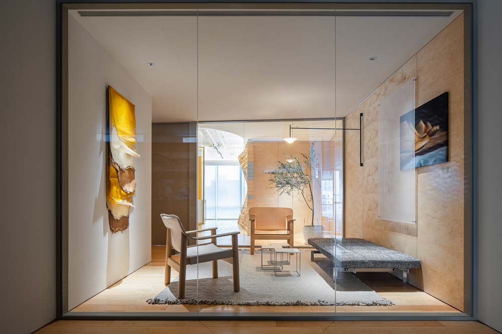 Salle de réunion vitrée avec sièges, banquette, mur en bois et un tapis gris