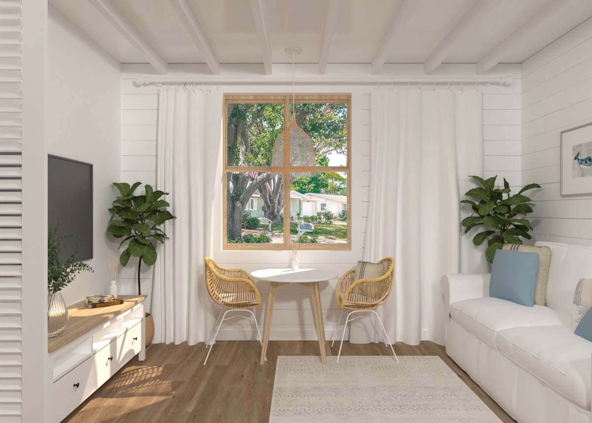 Un petit salon avec un canapé blanc, une télévision, une table et deux fauteuils en rotin