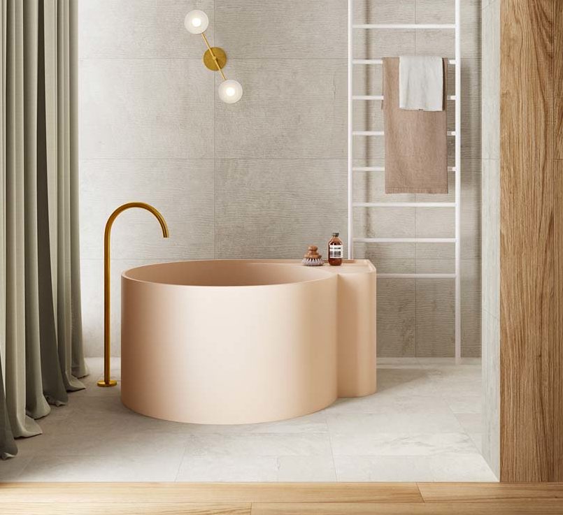 Une salle de bain avec une baignoire ronde rose pâle, du carrelage gris et des planches de bois décoratives