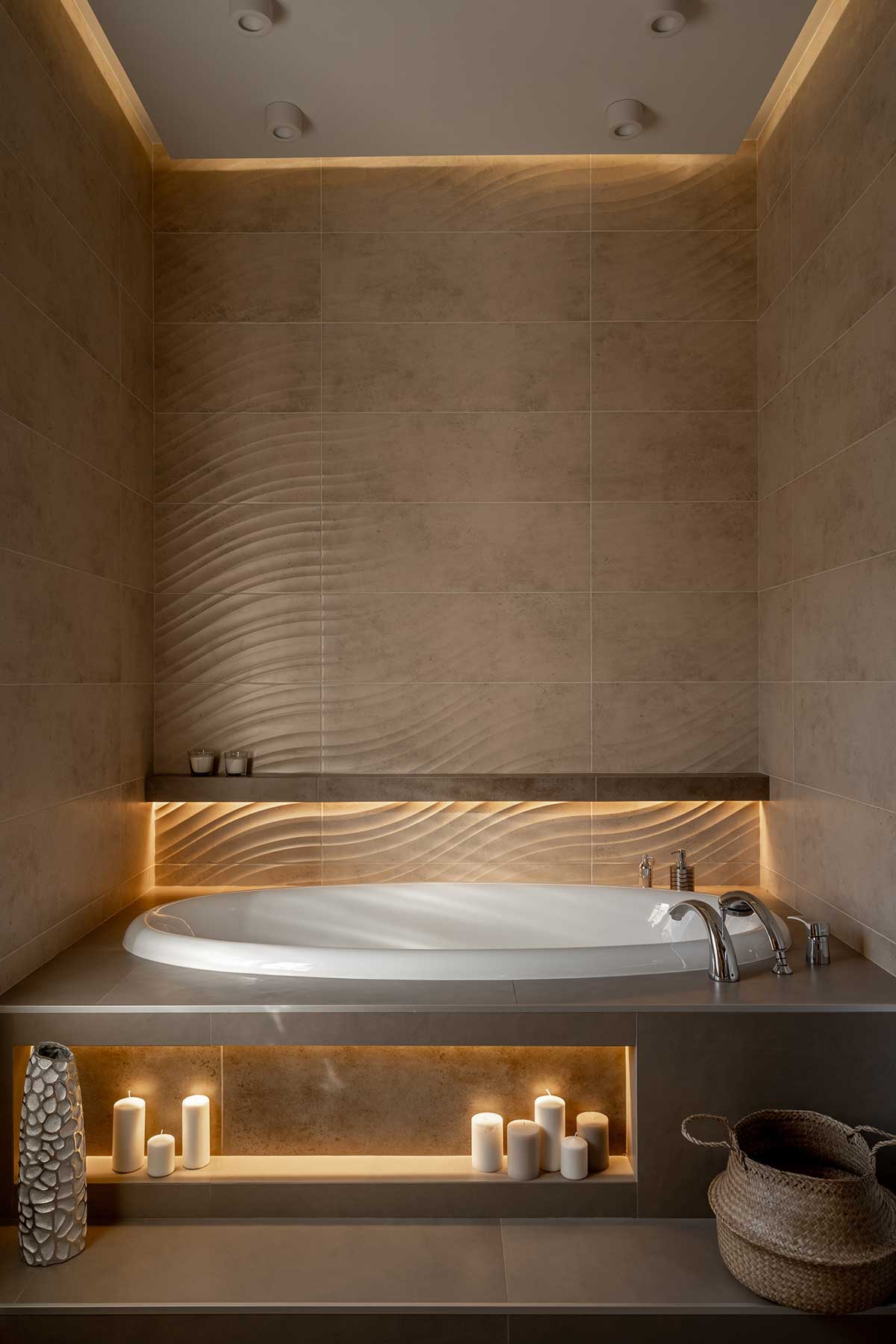 Une salle de bain tendance hamamm avec une grande baignoire ronde, des couleurs sable, des bougies et du carrelage ondulé