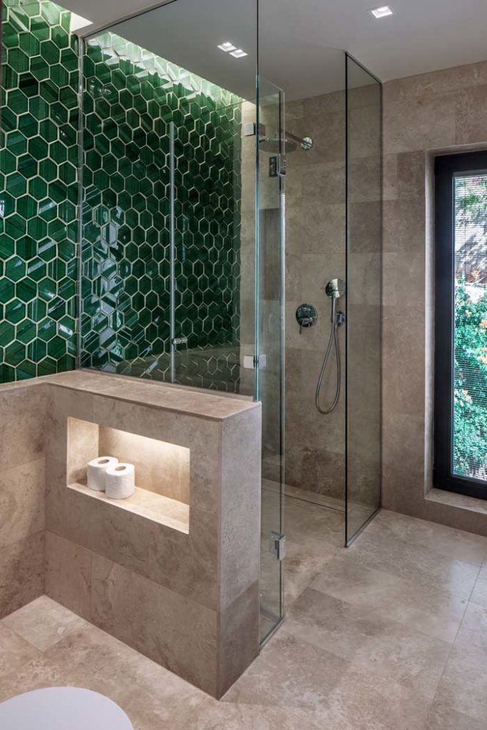 Une salle de bain grise moderne avec une grande cabine de douche transparente et un mur en zellige hexagonal vert émeraude