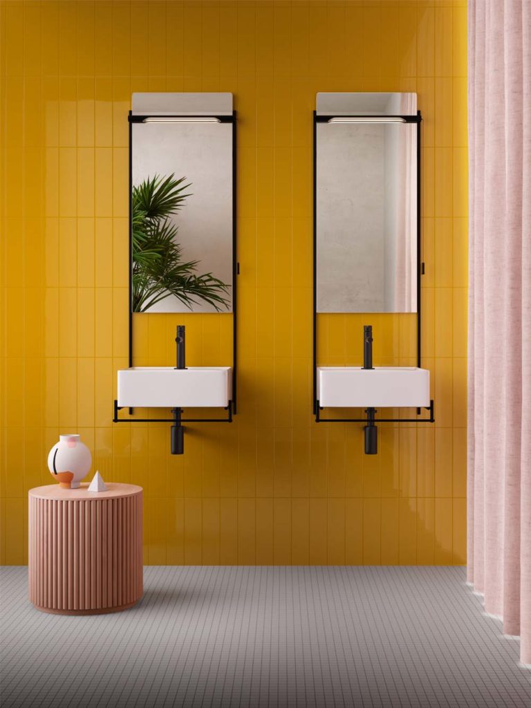 Salle de bain avec un mur en zellige jaune vif, un sol en carrelage blanc, de la petite déco rose et deux grands miroirs rectangulaires avec double vasques