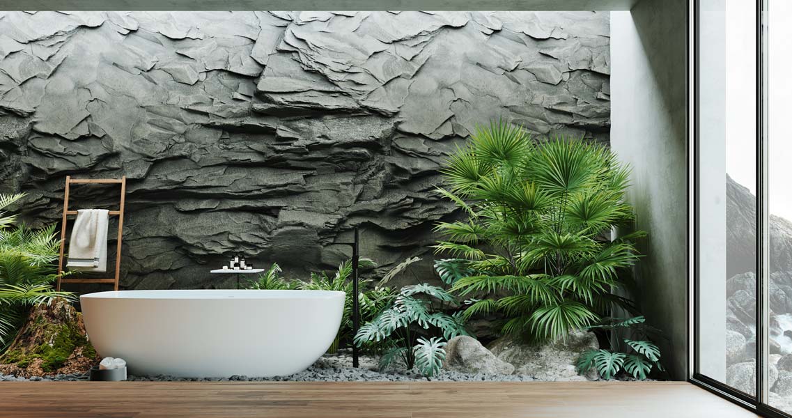 Une salle de bain zen et lumineuse avec un mur en pierre grise, un plancher en bois noble, une baignoire blanche, de la végétation et de la petite déco en bambou