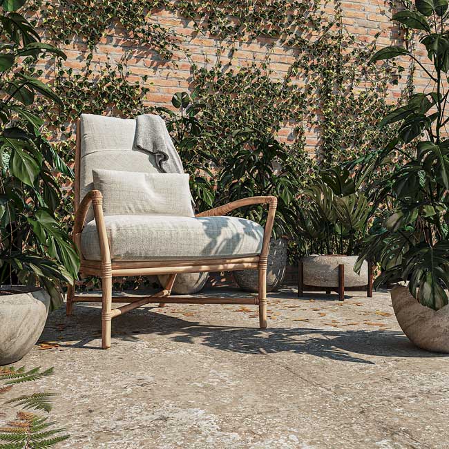 Un fauteuil lounge dans un jardin à l'ambiance méditerranéenne avec un mur en briques et des plantes grimpantes