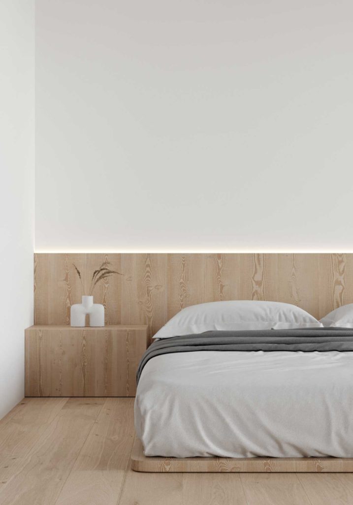 Le bois blond fait office de tête de lit, de table de nuit et surélève légèrement le matelas dans cette chambre minimaliste