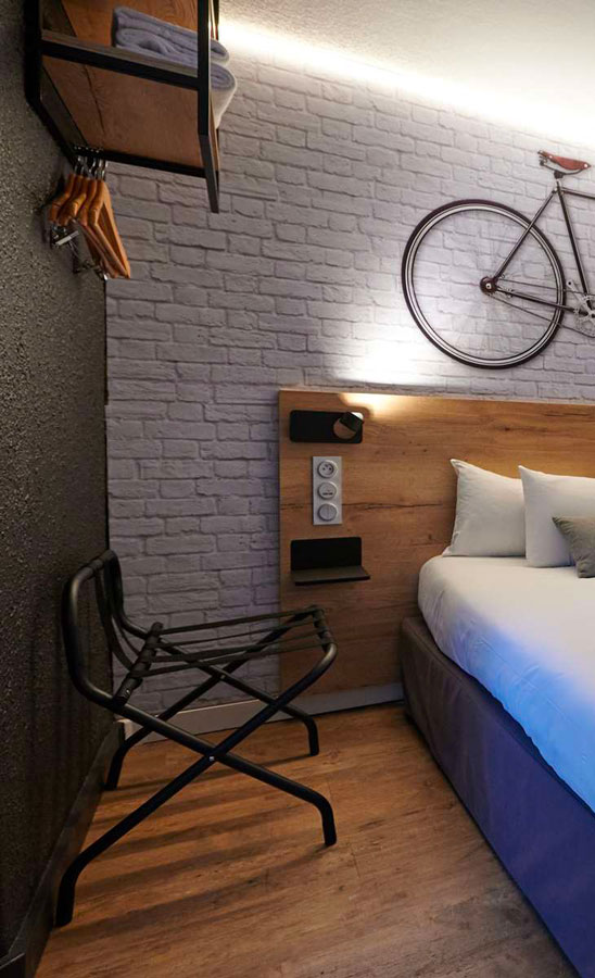 Chambre hôtel Kyriad Laval sur le thème du vélos avec mur effet pierre