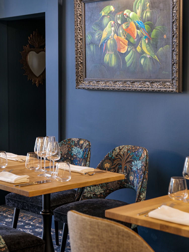 Décoration du Restaurant Arco avec des tables en bois, des murs bleus et des assises aux motifs ethniques.