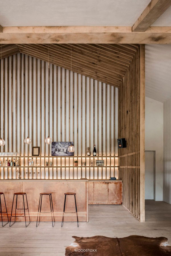 Un bar avec un soubassement en cuivre oxydé et un bardage en bois dans un intérieur rustique