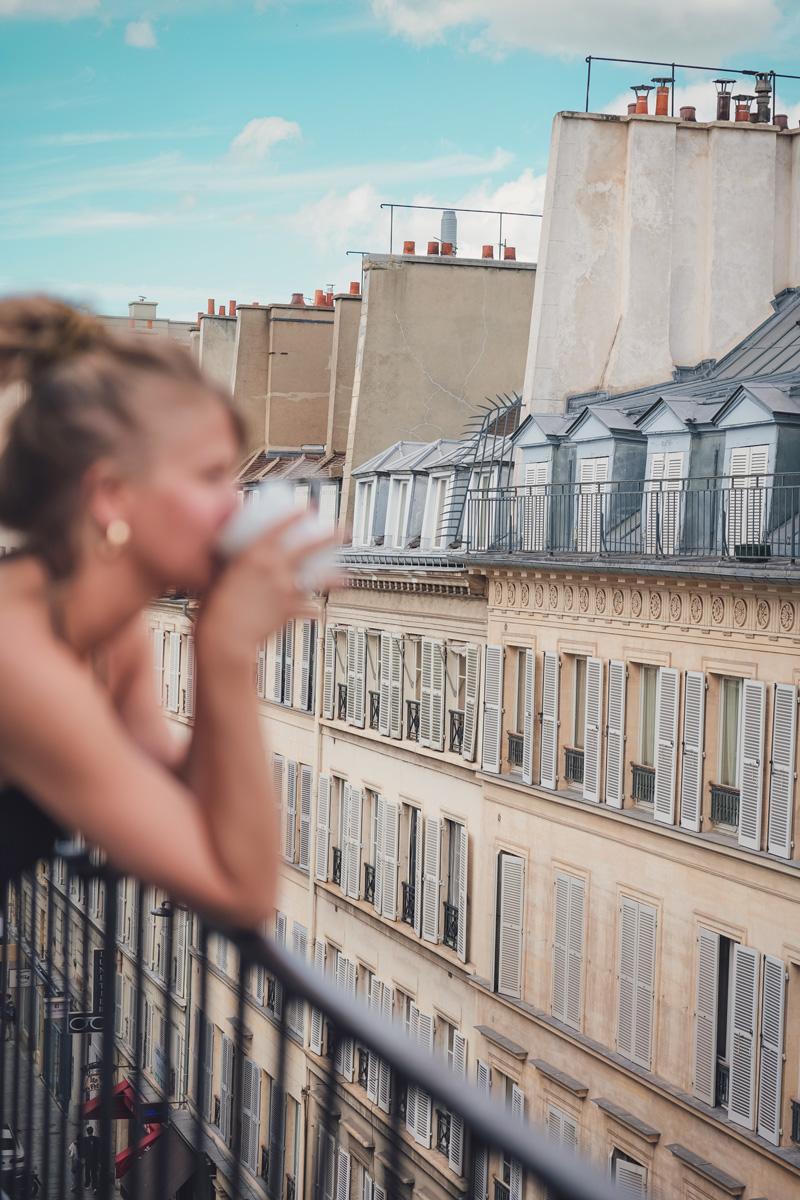 Cliente en haut du balcon de se chambre en train de boire un café.