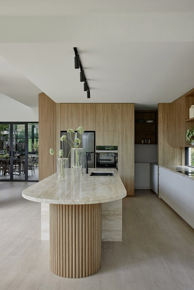 Cuisine plus moderne avec un plan de travail en granite beige et arrondi, avec des placard de cuisine avec une touche de bois.