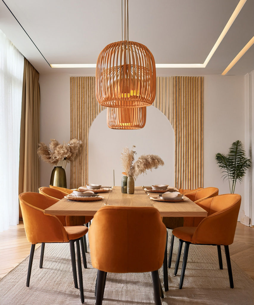 Table à manger en bois naturel, avec des chaises en velours orange, des luminaires, en osier orange, et dans le fond sur le mur un bardage en bois beige comme la table.