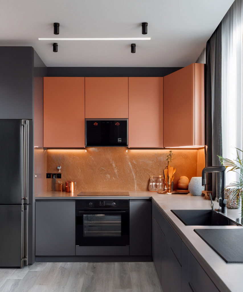 Cuisine moderne grise, avec quelques placards oranges et lumière laid blanche.