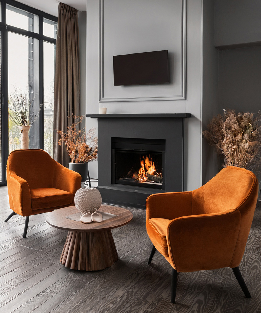 Salon cheminée, avec des fauteuils en velours orange couleur feu, le tout dans un ensemble gris et noir.