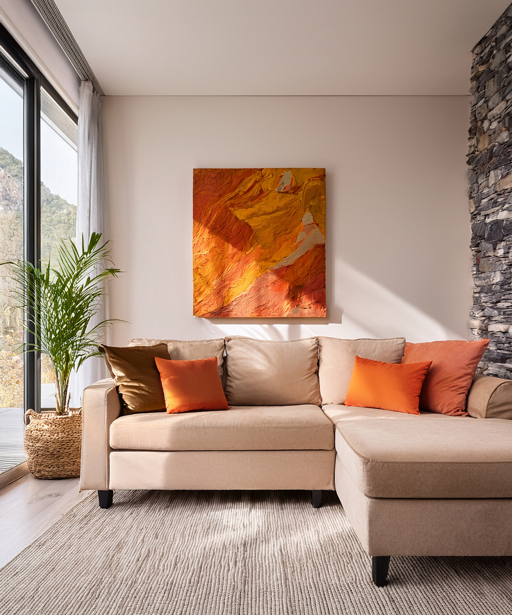 Salon avec canapé beige, des coussins aux couleurs de l'automne, marron, orange, orange clair. Ainsi qu'un grand tableau aux couleurs des feuilles de l'automne, dans un décor beige.
