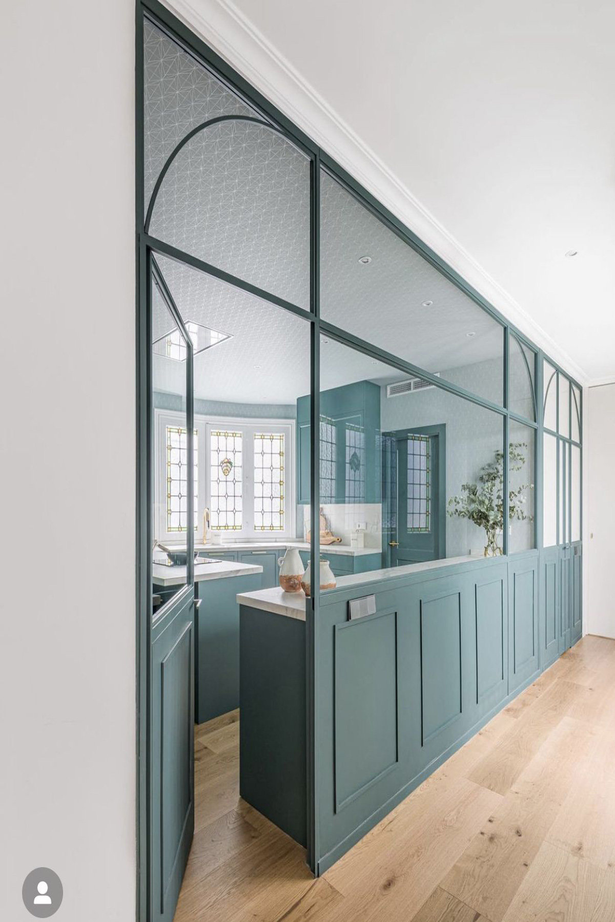 Séparation cuisine et salon, avec verrière rectangulaire et une porte.