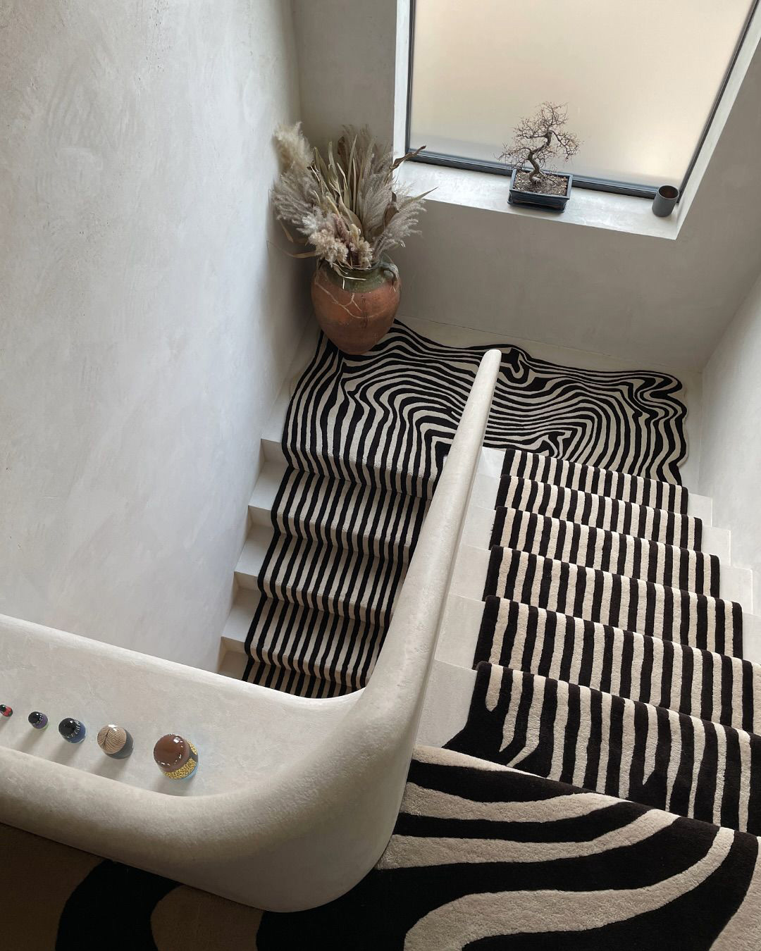 Escalier avec tapis noire et blanc avec des formes ondulés qui donne un effet de sens pour circuler.