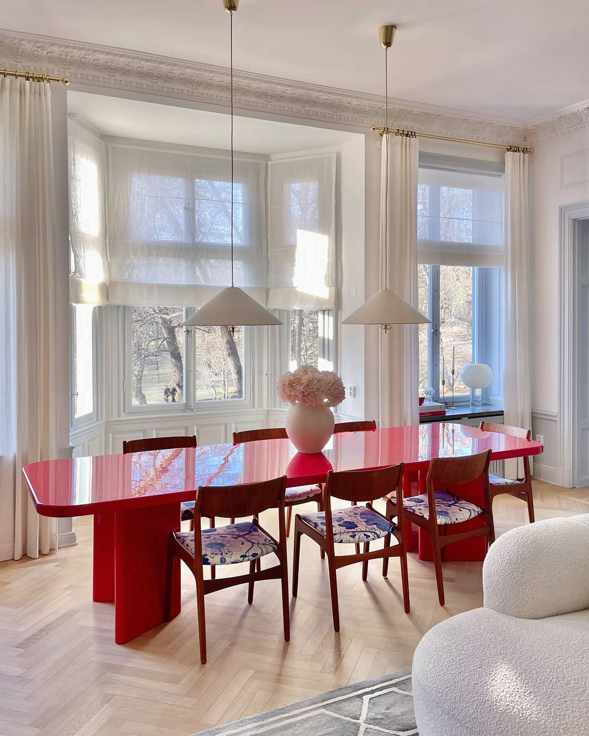 Grand salon d’appartement aux tons beige et blanc avec table basse rouge clair.