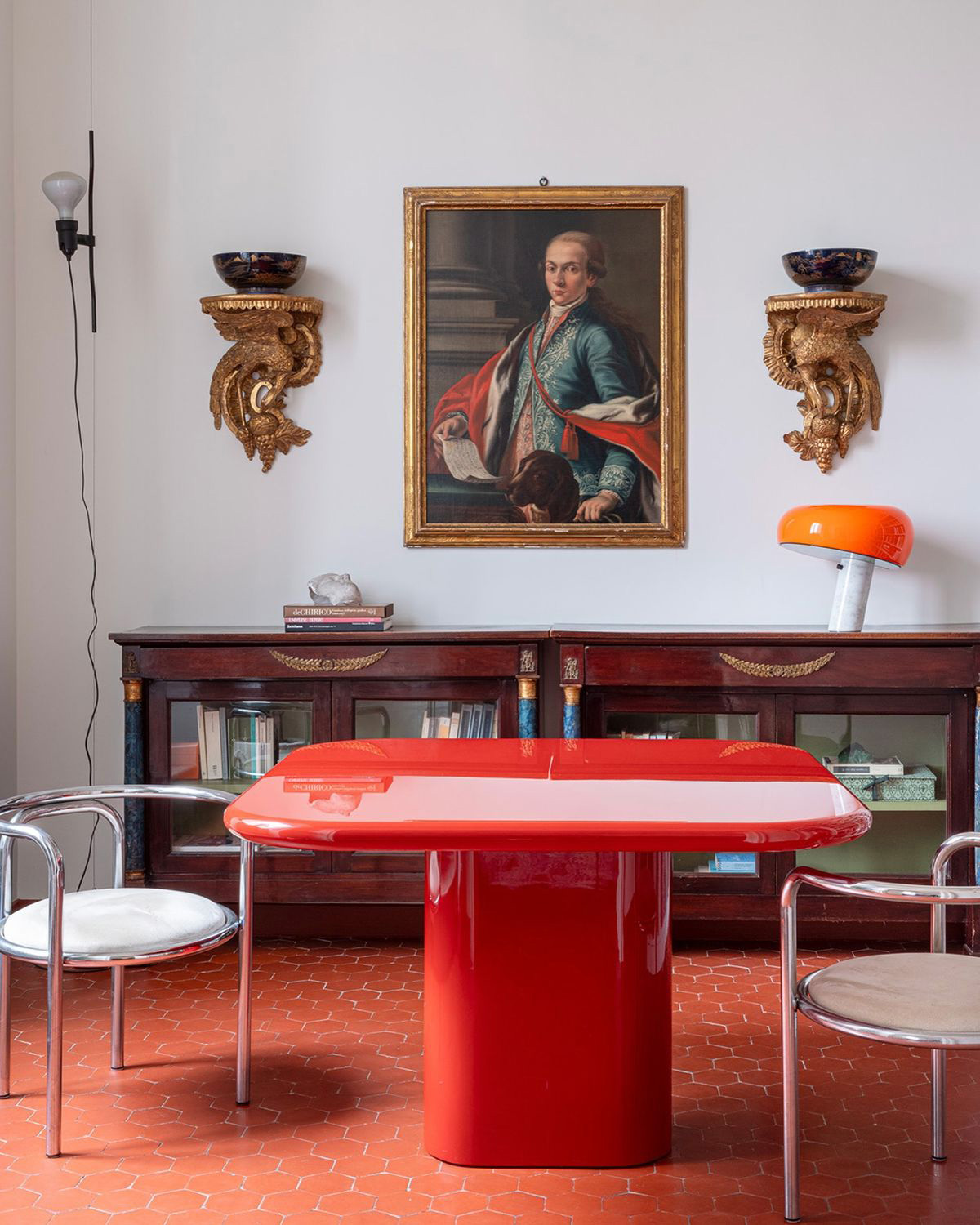 Salle à manger avec table carrée rouge brillante dans un intérieur ancien.